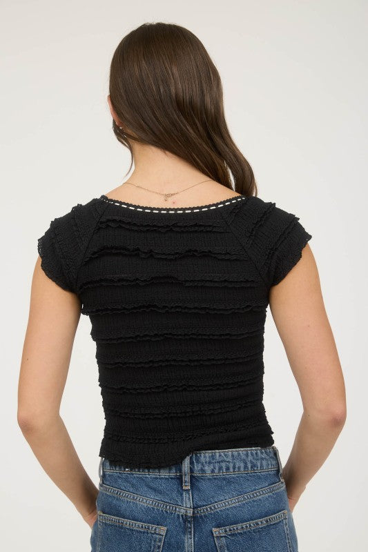 Woman wearing a black ruched top and blue jeans on a white background