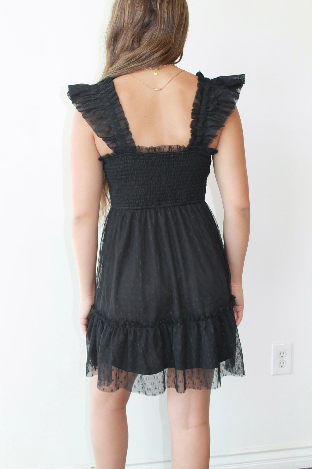 Black dress with ruffled straps and lace details on a white background