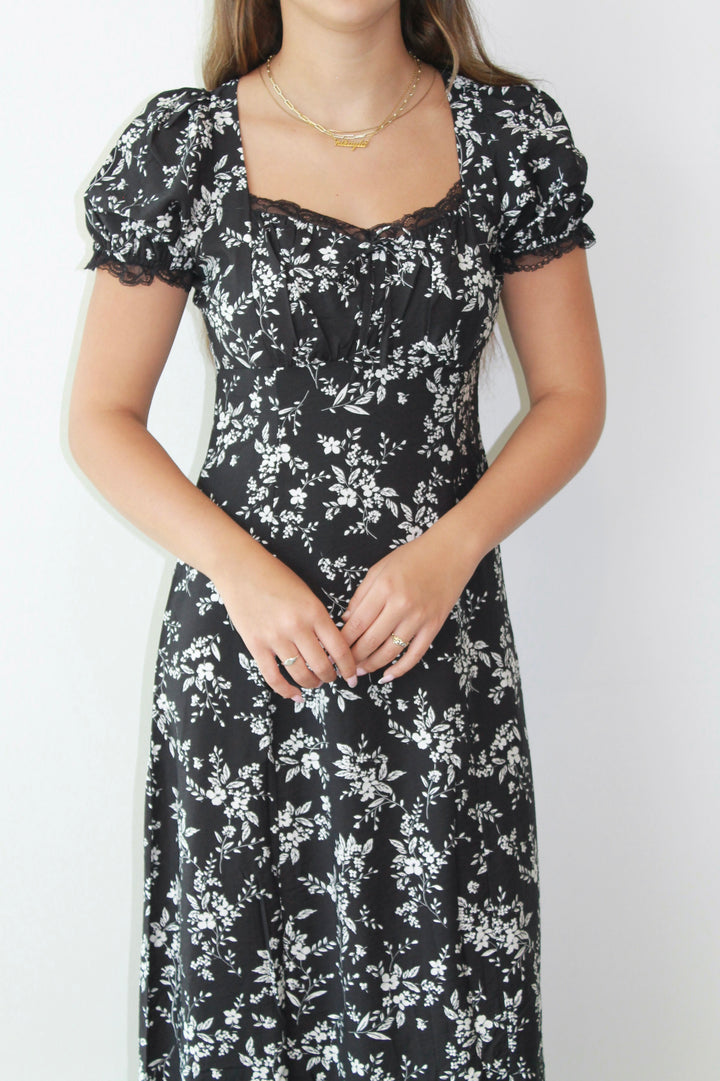 Woman wearing a black floral dress against a white background