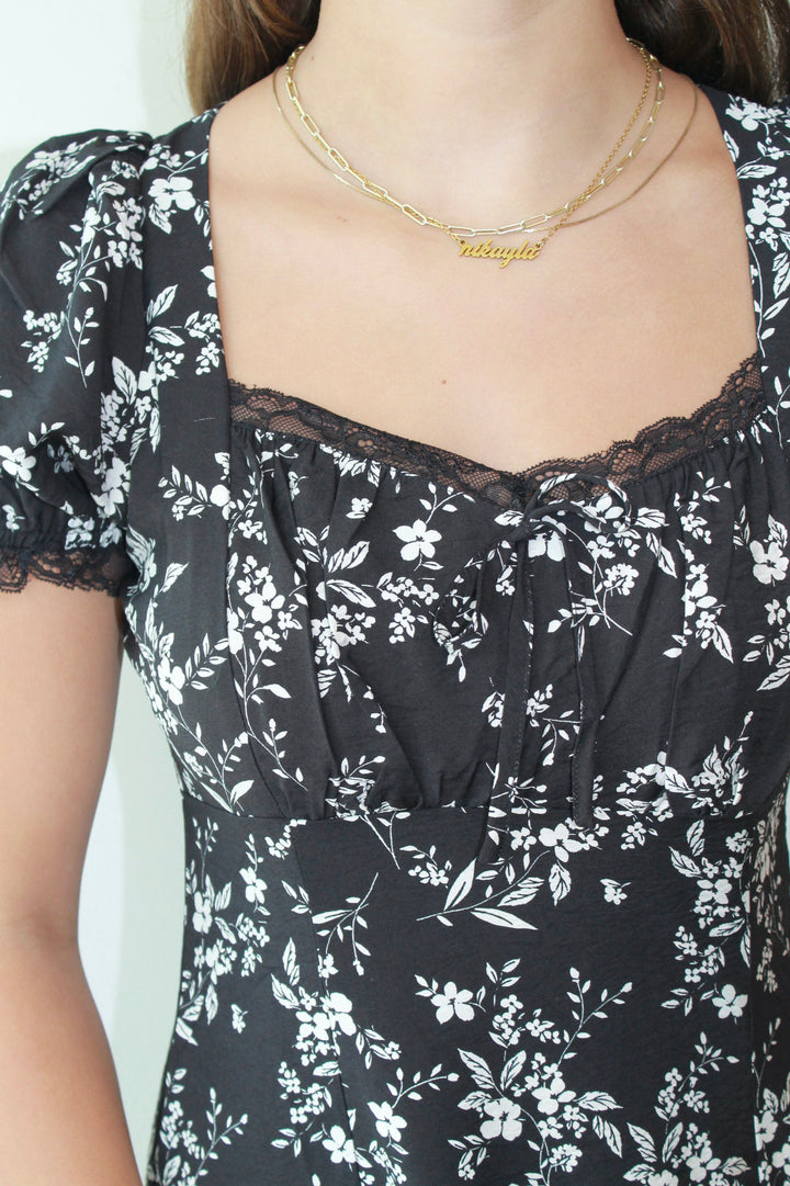 Black floral dress with lace details and a gold necklace.