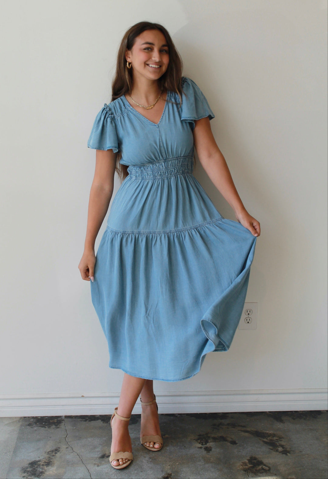 Woman wearing a light blue dress against a white wall
