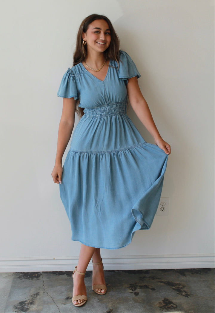 Woman wearing a light blue dress against a white wall
