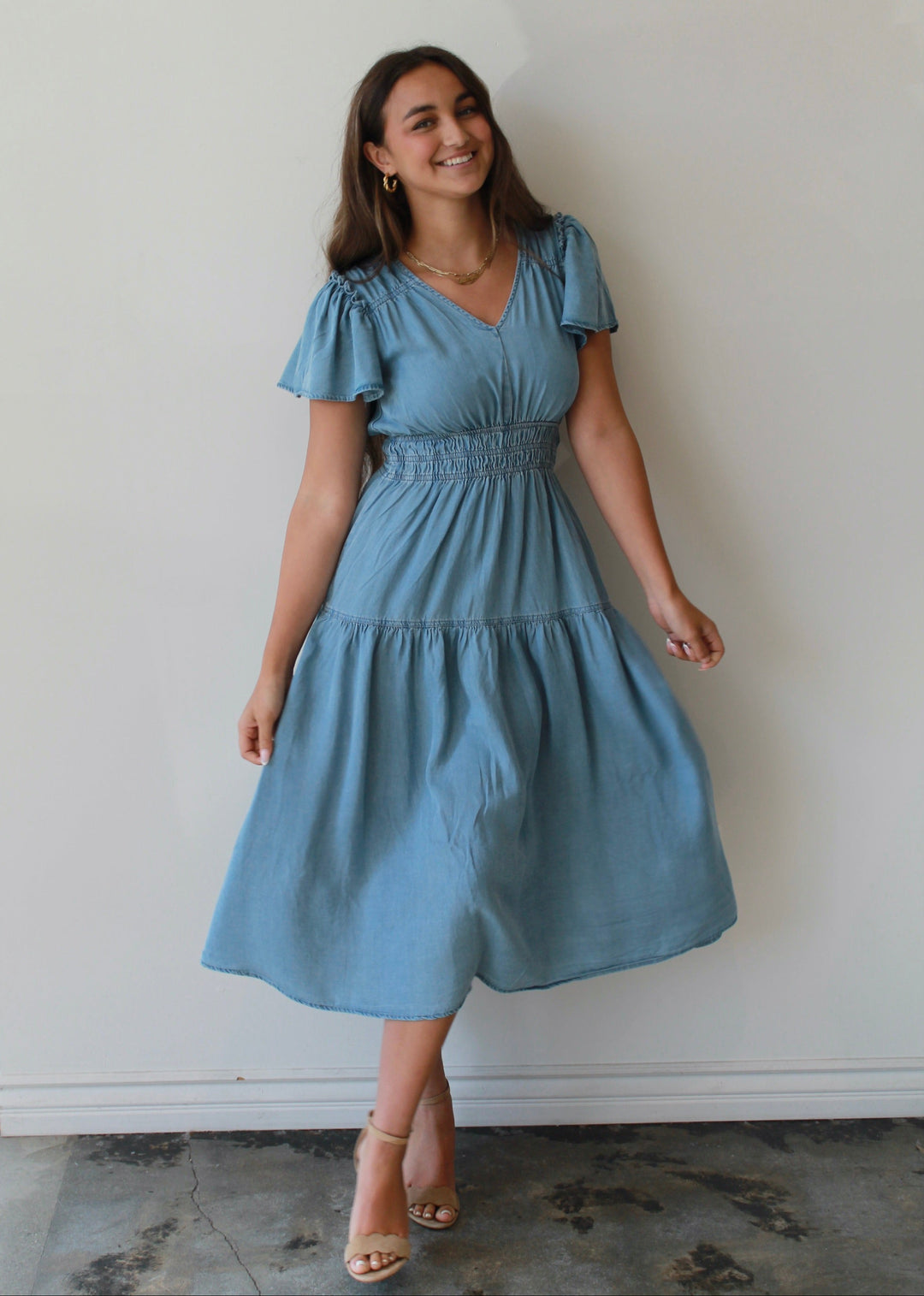 Woman wearing a blue dress standing against a white wall