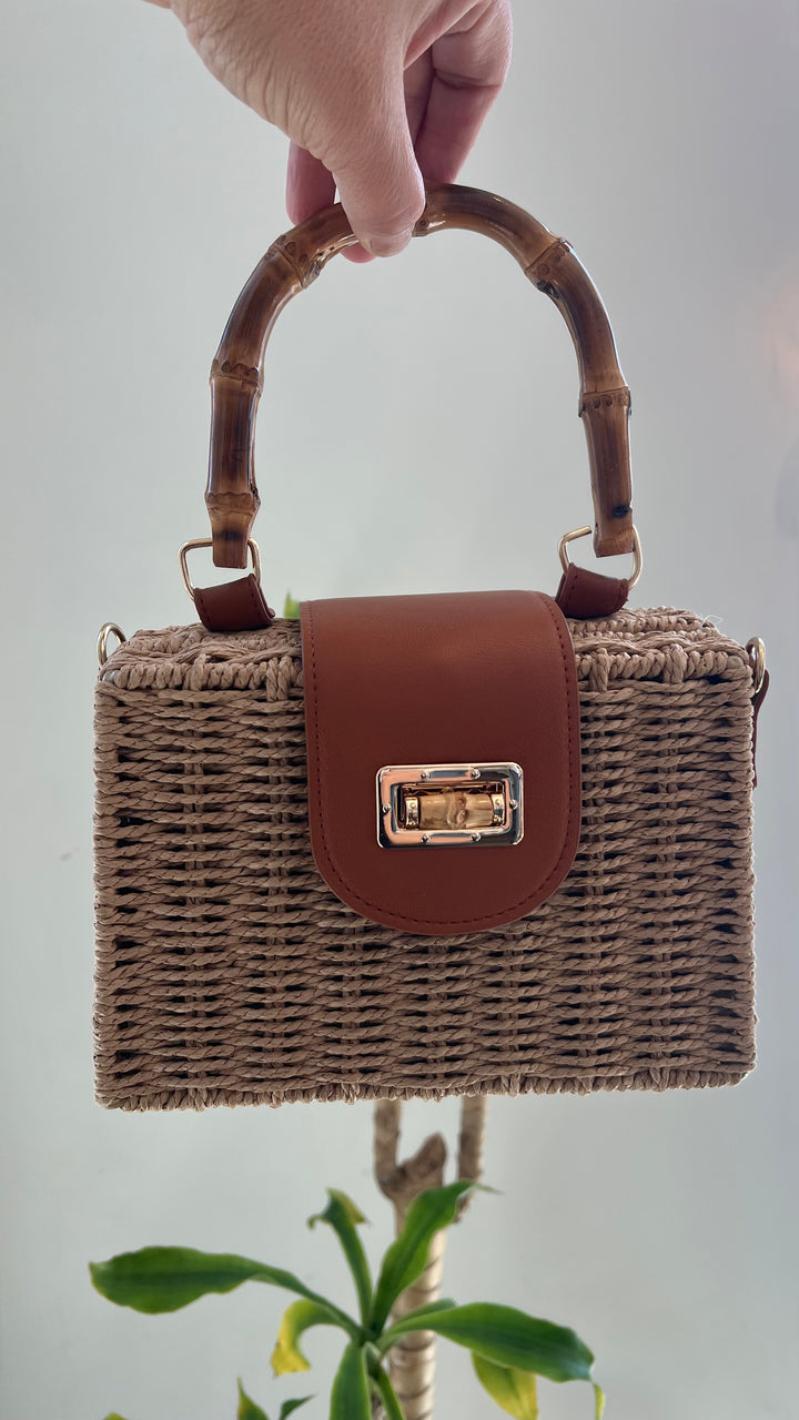 Structured woven straw purse with bamboo handles, gold clasp closure, and removable tan crossbody strap.