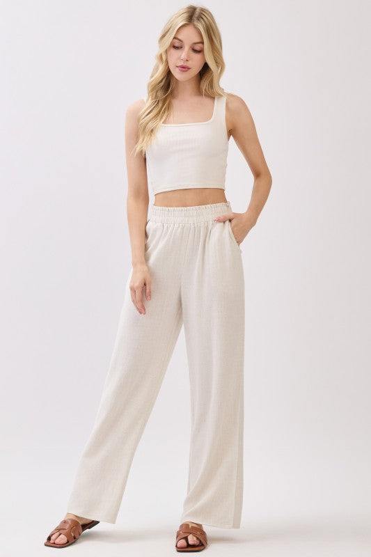 Beige linen wide leg pants styled with cropped tank top and sandals
